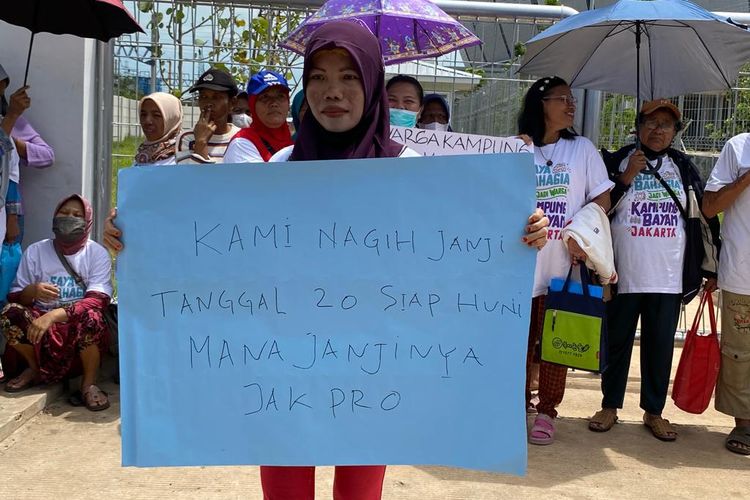 Sala satu warga menunjukkan poster berisi tuntutan untuk bisa segera menempati Kampung Susun Bayam. Warga melakukan unjuk rasa pada Senin (21/11/2022) di depan gerbang rusun. 
