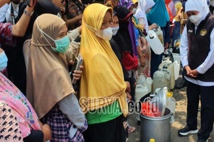 Gubernur Jawa Timur Khofifah Indar Parawansa saat mengobrol dengan pedagang yang antre minyak goreng murah dengan membawa dandang nasi besar. 