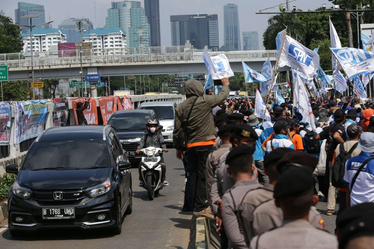 Pengguna jalan melintasi jalur Transjakarta saat terjadi demonstrasi dari elemen buruh  depan Gedung DPR/MPR RI, Jakarta, Selasa (6/9/2022). Mereka menolak kenaikan harga BBM.