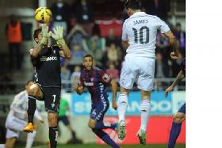 Gelandang Real Madrid, James Rodriguez (kanan), menyundul bola yang menghasilkan gol ke gawang Eibar, meski berusaha dihalau kiper Irureta (kiri), dalam laga Primera Division, Sabtu (22/11/2014).