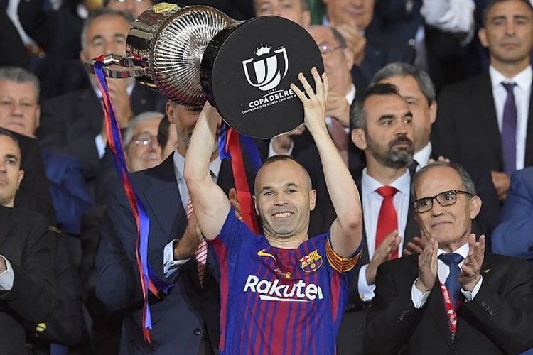 Kapten Barcelona, Andres Iniesta, mengangkat trofi juara Copa del Rey 2018 yang diraihnya pasca mengalahkan Sevilla 5-0 di Stadion Wanda Metropolitano, Madrid, pada Minggu (22/4/2018).