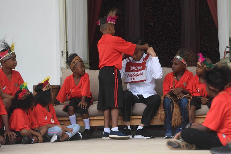 Presiden Joko Widodo menerima noken pemberian anak-anak perwakilan siswa SD di Jayapura dan Asmat, Papua, di Istana Merdeka, Jakarta, Jumat (11/10/2019). Kedatangan anak-anak tersebut dalam rangka memenuhi undangan presiden, yang dulu berjanji mengajak mereka ke Istana Kepresidenan saat mengunjungi Jayapura dan Asmat.