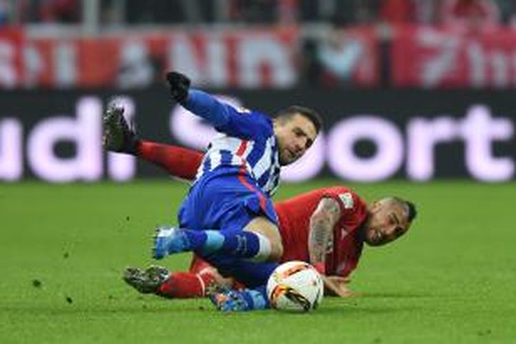 Striker Hertha Berlin asal Bosnia, Vedad Ibisevic (kiri), berebut bola dengan gelandang Bayern Muenchen asal Cile, Arturo Vidal, pada laga Bundesliga di Allianz Arena, Sabtu (28/11/2015).