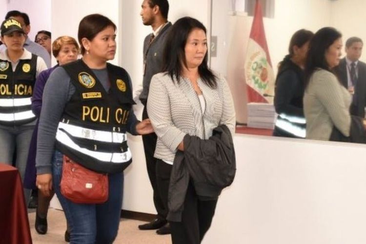 Keiko Fujimori, pemimpin oposisi dan putri mantan presiden Peru Alberto Fujimori, dikawal oleh petugas polisi di kantor Kehakiman, di Lima. Dia ditangkap pada Rabu (10/10/2018) karena dugaan pencucian uang yang melibatkan raksasa konstruksi Brasil, Odebrecht. (AFP/Juan Carlos VIVAS/ Peruvian Judiciary)