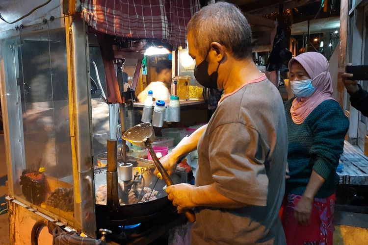 Dartadi penjual nasi goreng di Jalan Muharto gang VB Kota Malang saat menggunakan mesin untuk mengaduk nasi goreng yang sedang diraciknya, Kamis (14/10/2021) malam.