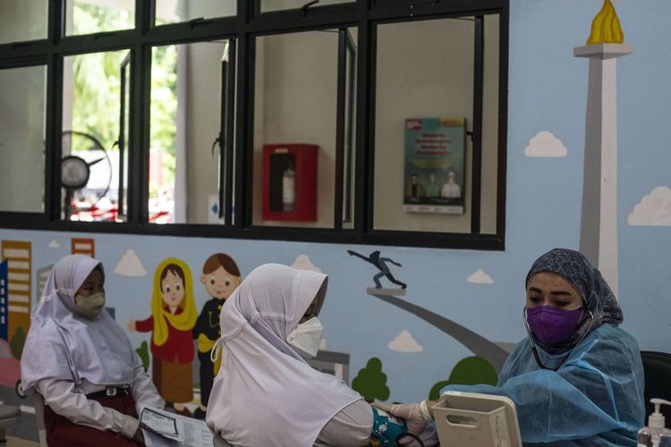 Tenaga kesehatan (kanan) melakukan pemeriksaan kesehatan kepada pelajar sebelum menyuntikkan vaksinasi Covid-19 di SDN Cempaka Putih Timur 03, Jakarta, Selasa (14/12/2021). Kementerian Kesehatan memulai vaksinasi Covid-19 untuk anak usia 6-11 dengan jumlah sasaran vaksinasi mencapai 26,5 juta di Indonesia.