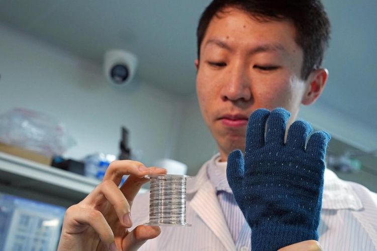 Seorang peneliti memperlihatkan cip serat yang digulung serta sarung tangan taktil pintar yang dibuat dengan menenunkan cip tersebut ke dalam tekstil di Universitas Fudan, Shanghai, China timur, pada 19 Januari 2026.