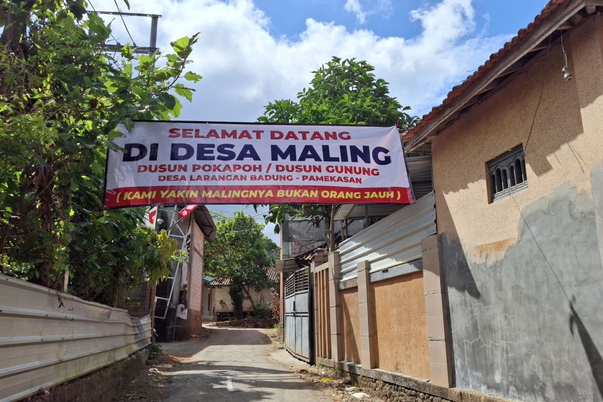 Baliho bertuliskan selamat datang di desa maling dipasang oleh warga Desa Larangan Badung, Pamekasan, Rabu (20/8/2025)