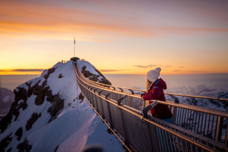 Tempat wisata di Swiss - Seorang wisatawan sedang melihat pemandangan dari Peak Walk by Tissot Suspension Bridge di Glacier 3000.