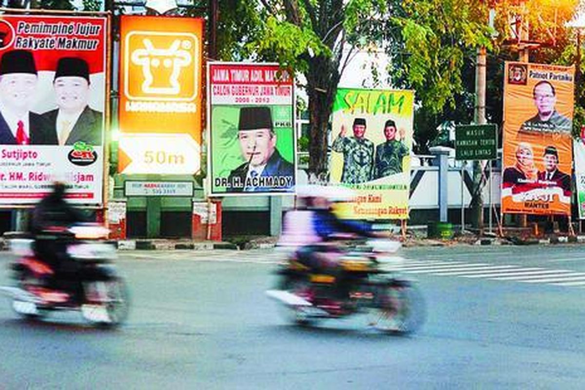 Baliho bergambar lima pasang calon gubernur dan wakil gubernur yang ditetapkan menjadi peserta pilkada oleh Komisi Pemilihan Umum (KPU) Jawa Timur masih terpasang di salah satu sudut Jalan Raya Darmo, Surabaya, Minggu (15/6). Panitia Pengawas Pilkada meminta semua alat peraga bergambar pasangan calon yang resmi ditetapkan KPU diturunkan karena belum memasuki masa kampanye resmi.  