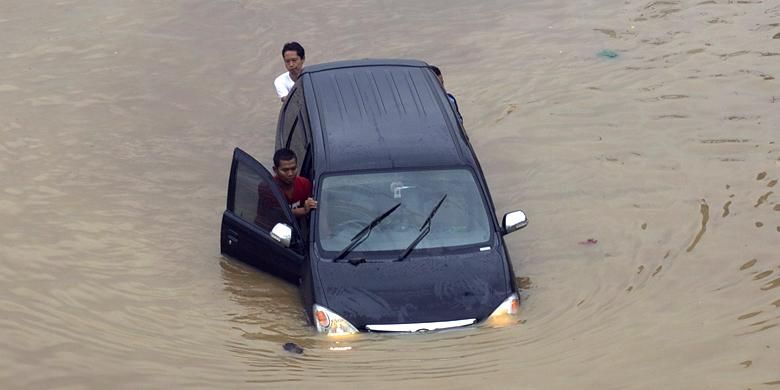 Luapan Kali Ciliwung memutus jalur kendaraan di Jalan KH Abdullah Syafi'ie, Tebet, Jakarta Selatan, Senin (13/1/2014). Luapan kali mulai menggenangi permukiman dan memutus jalan sejak Senin dini hari.