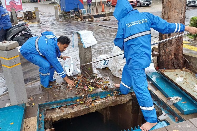 Petugas pompa air dari Suku Dinas Sumber Daya Air (SDA) Jakarta Selatan bahu-membahu membersihkan sampah di saluran air yang terletak di Jalan Kemang Raya, Jakarta Selatan, Kamis (4/1/2024).