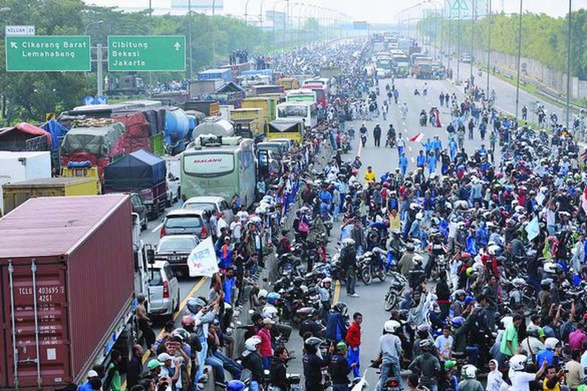 Buruh berunjuk rasa dengan menutup Jalan Tol Jakarta-Cikampek di sekitar Pintu Tol Cikarang Barat, Bekasi, Jawa Barat, Jumat (27/1).