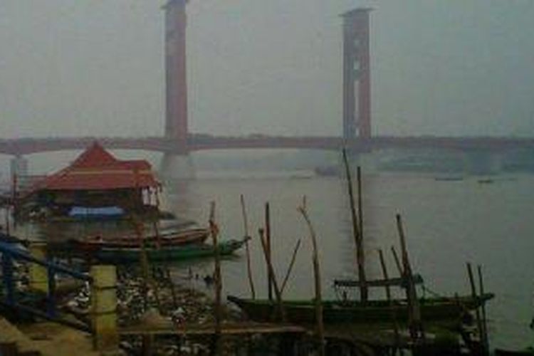 Jembatan Ampera terlihat tidak jelas karena diselimuti kabut asap dari kebakaran lahan di Sumsel yang hingga kini makin tebal. 