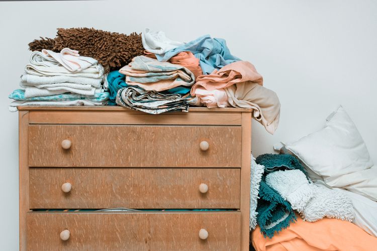 Ilustrasi tumpukan pakaian di kamar tidur yang bisa menjadi sumber kekacauan.