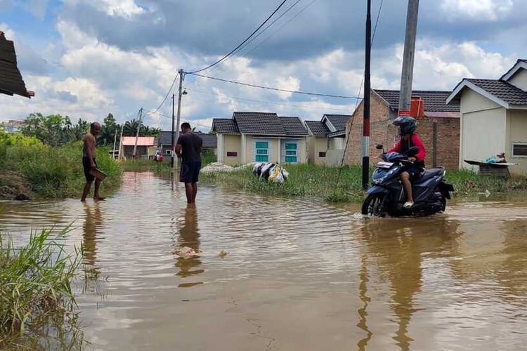 Warga mengarungi banjir untuk melihat barang-barang di rumahnya di Perumahan Pesona Harapan Indah, Kelurahan Tangkerang Labuai, Kecamatan Bukitraya, Kota Pekanbaru, Riau, Selasa (26/10/2021).