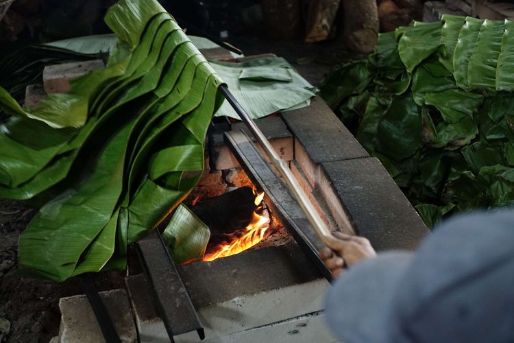 A number of workers burned pieces of banana leaves to wrap basket cakes at the Dodol and Ny Cake production house. Lauw (LKW), in Tangerang, Banten, Friday (17/1/2025). The burning process uses chunks of tree trunks.