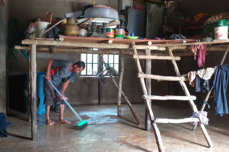 Budiman (38) tengah membersihkan lumpur yang melekat di lantai rumahnya pasca banjir di Desa Buluh Cina, Kecamatan Siak Hulu, Kabupaten Kampar, Riau, Kamis (2/1/2020).