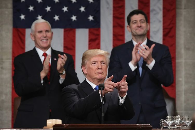 Presiden AS Donald Trump menyampaikan pidato kenegaraan. Di belakangnya berdiri Wakil Presiden AS Mike Pence (kiri) dan Ketua DPR AS Paul Ryan (kanan) bertepuk tangan di majelis Dewan Perwakilan AS di Washington DC, pada Selasa (30/1/2018). (Win McNamee/POOL/AFP)