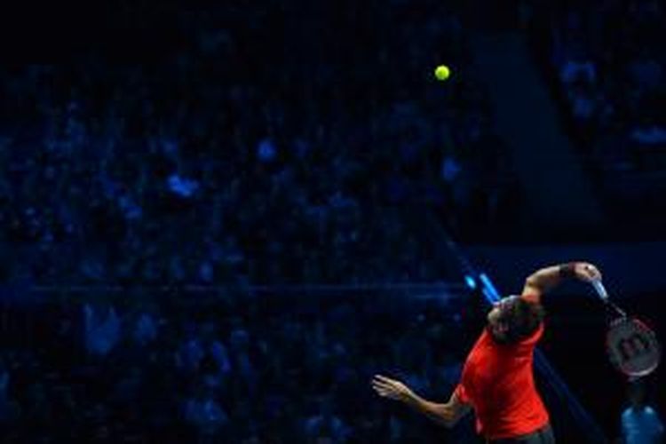 Petenis Swiss, Roger Federer, melakukan servis saat menghadapi petenis Kanada, Milos Raonic, pada babak round robin Grup B ATP World Tour Finals di O2 Arena, London, Minggu (9/11/2014).