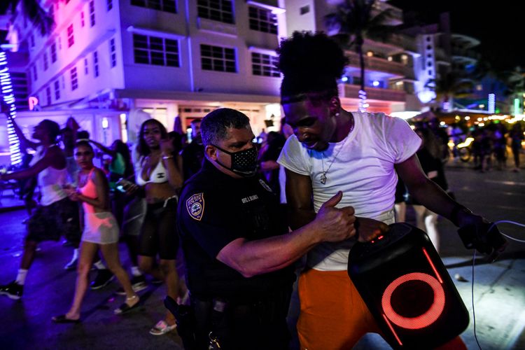 Foto tertanggal 17 Maret 2021 menunjukkan Polisi Pantai Miami menahan seorang pria yang memainkan musik keras dengan speaker nirkabel di Ocean Drive, Miami Beach.