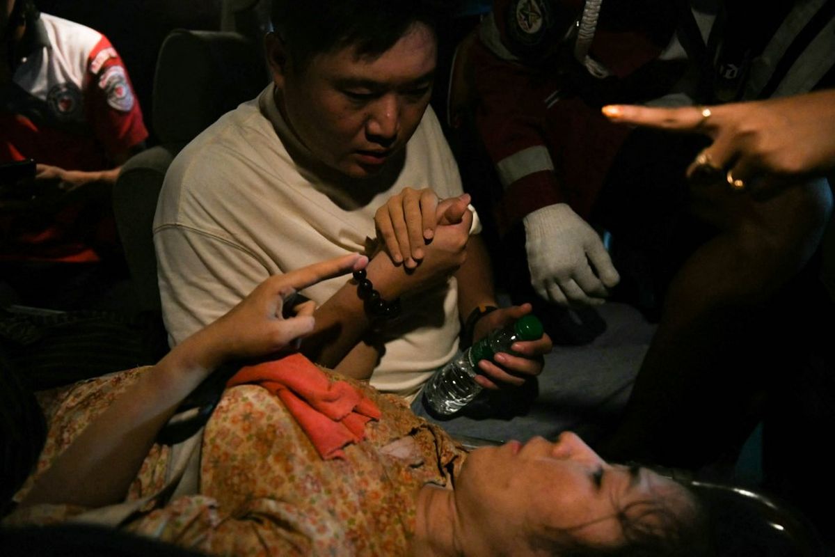 Ye Aung (tengah) menemani istrinya Phyu Lay Khaing dalam perjalanan ke rumah sakit setelah dia diselamatkan dari reruntuhan gedung apartemen Sky Villa Condominium yang runtuh di Mandalay pada 29 Maret 2025, sehari setelah gempa Myanmar. Tim penyelamat mengeluarkan seorang perempuan hidup-hidup dari reruntuhan gedung apartemen yang runtuh di Mandalay pada 29 Maret, wartawan AFP melihat, 30 jam setelah gempa dahsyat melanda Myanmar.