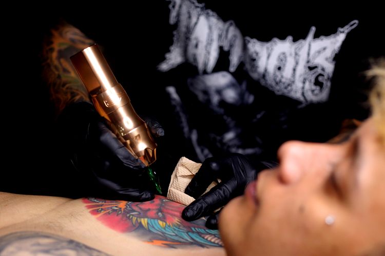  Ferry Irawan, tattoo artist saat sedang menato kliennya di Epic Tattoo Studio di daerah Soekarno-Hatta Kota Malang, Selasa (11/2/2025) malam.