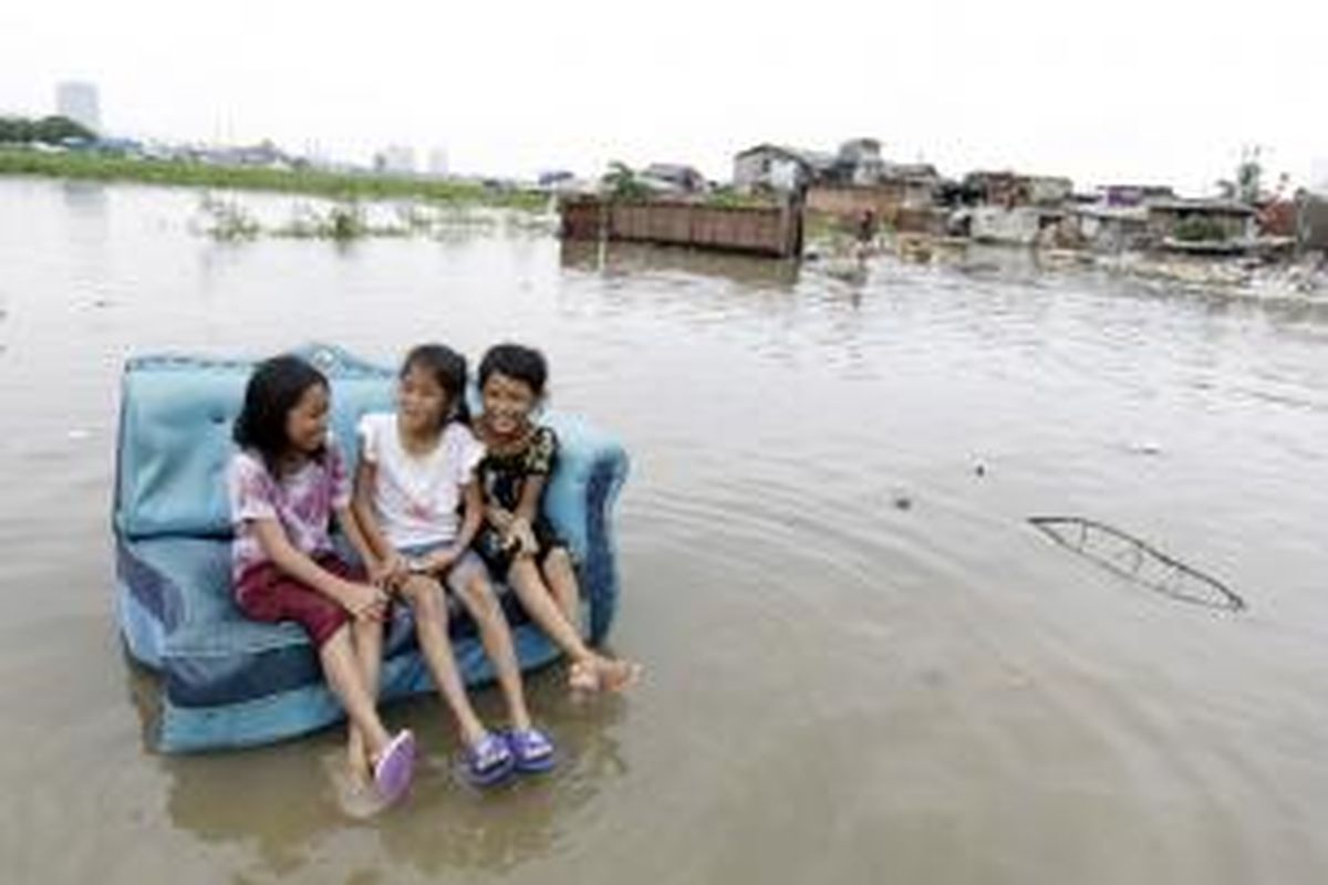 Anak-anak bermain di sekitar banjir yang terjadi akibat meluapnya Waduk Pluit, Jakarta Utara, Minggu (19/1/2014).  
