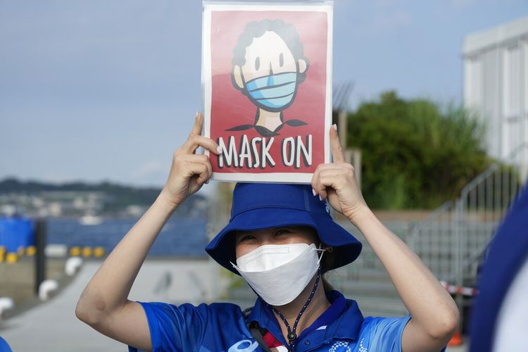 Dalam foto arsip 1 Agustus 2021 ini, sukarelawan Olimpiade Reimi Kusunoki memegang tanda di pelabuhan kapal pesiar Enoshima selama Olimpiade Musim Panas 2020 di Fujisawa, Jepang.