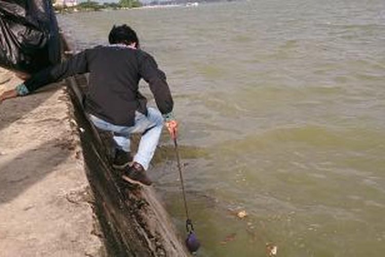 Seorang pencinta lingkungan terlihat memungut sampah dari Teluk Kendari dengan memakai tongsis. Ini dilakukan dalam rangka peringatan Hari Lingkungan Hidup Se-Dunia.
