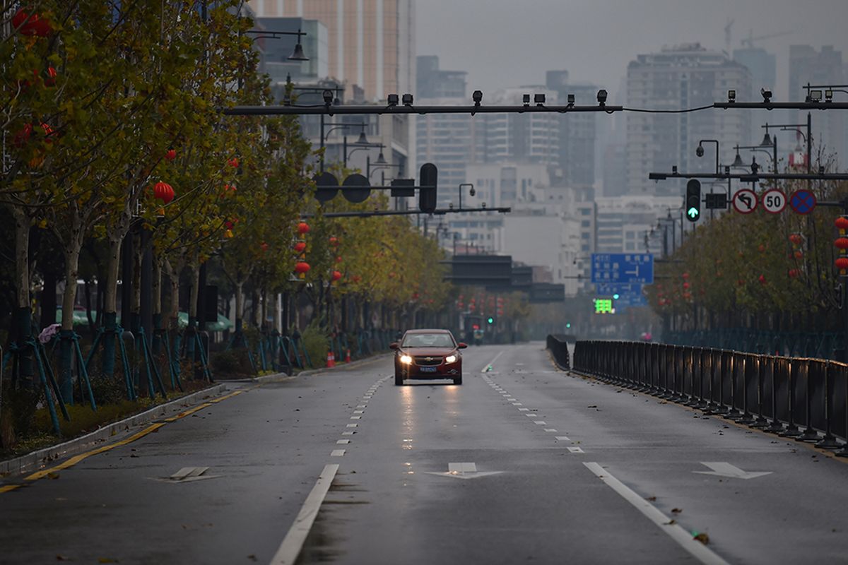 Sebuah mobil melaju sendiri di jalanan kota Wuhan, China, yang sepi akibat wabah virus corona yang mematikan, Minggu (26/1/2020).