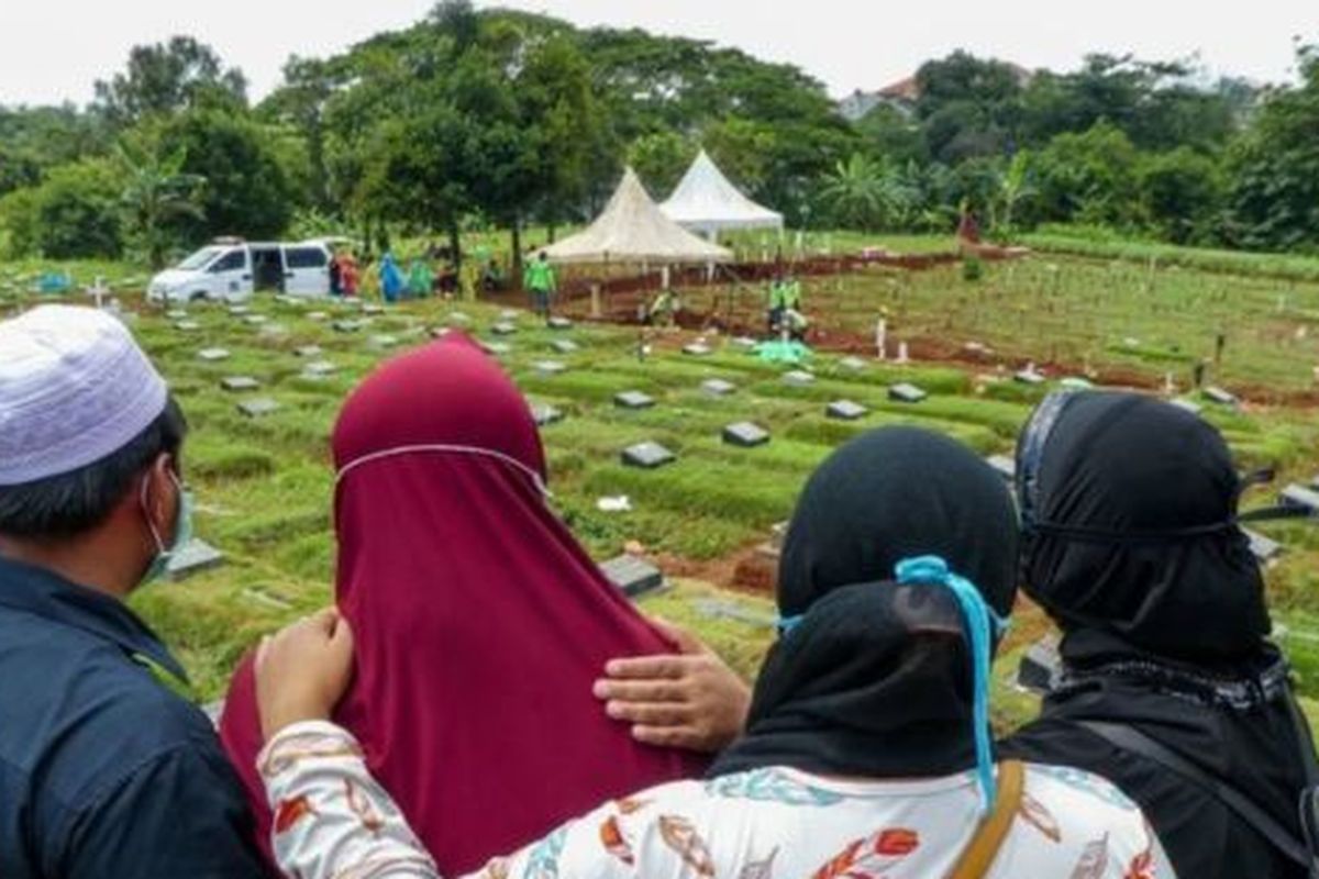 Keluarga memantau dari jauh pemakaman salah satu anggotanya yang meninggal karena Covid-19. 