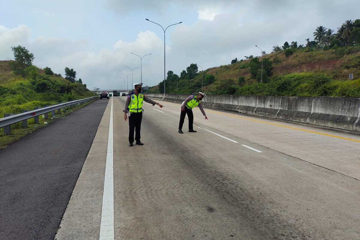 Anggota Satlantas Polres Lampung Selatan menunjukkan lokasi kecelakaan yang menewaskan dua orang di Jalan Tol Lampung KM 08+700 Jalur B, Lampung Selatan.