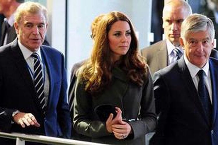 Catherine the Duchess of Cambridge atau yang lebih terkenal dengan nama Kate Middleton (tengah) --istri Pangeran William-- berjalan ditemani eks pemain timnas Inggris, Trevor Brooking (kiri), dan Chairman FA, David Bernstein, dalam acara peresmian Pusat Sepak Bola Nasional FA di St Georges Park, Selasa (9/10/2012). 