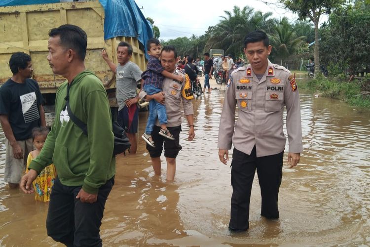 Kapolsek Ukui, Iptu Rudi Hardiyono (depan kanan) bersama anggotanya membantu warga melewati banjir, di Desa Lubuk Kembang Bunga, Kecamatan Ukui, Kabupaten Pelalawan, Riau, Sabtu (13/1/2024).