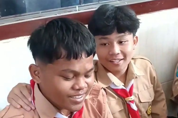 Enggar saat dirangkul temannya dalam momentum pemberian sepatu. Rekan-rekan Enggar di SMK PGRI 1 Kota Kediri, Jawa Timur, patungan dari uang jajann untuk membelikannya sepatu lalu video itu viral.