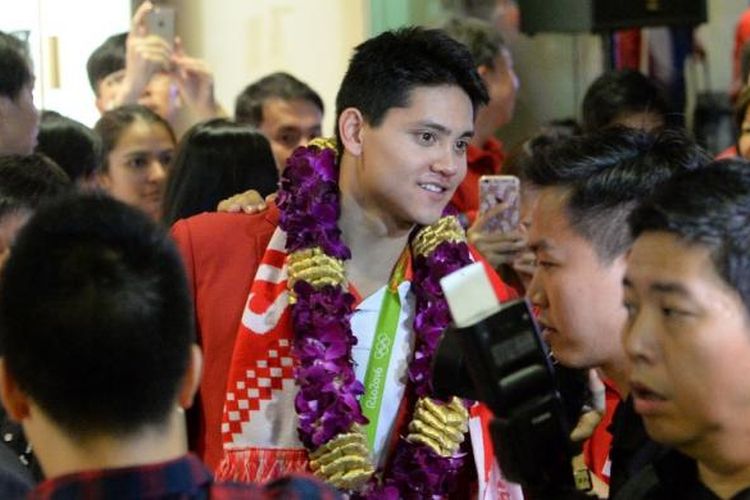 Perenang Singapura, Joseph Schooling (tengah), tiba di Bandara Changi, Senin (15/8/2016), setelah berlomba pada Olimpiade Rio 2016. Dia menjadi atlet Singapura pertama yang meraih medali emas Olimpiade.