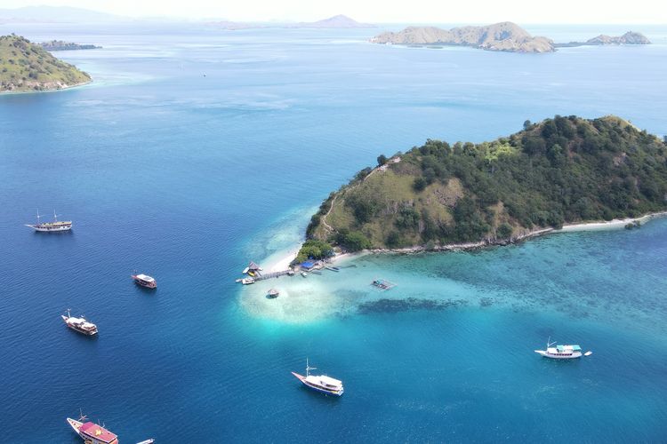 Panorama pantai dan kapal turis di Pulau Kelor, Taman Nasional Komodo, Labuan Bajo.