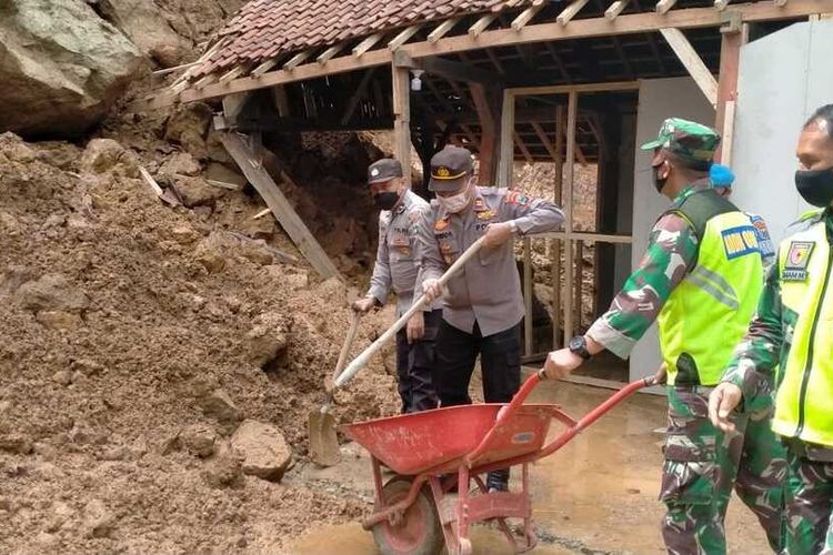 Anggota Babinsa, Bhabinkamtibmas serta warga membersihkan materila longsor yang menimpa rumah warga dusun Krajan Desa Joho kecamatan Pule Trenggalek Jawa Timur, Senin (01/11/2021).
