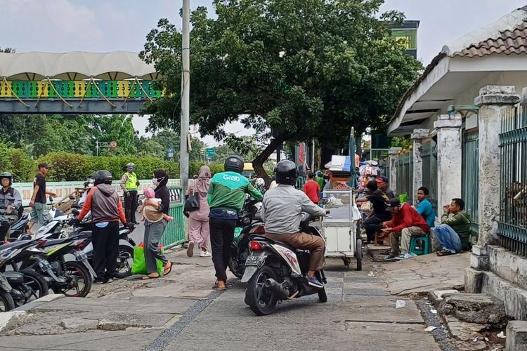 Saat pengendara motor menuntun motornya untuk mengelabui petugas kepolisian saat melawan arah di lampu merah Stasiun Pasar Minggu, Jakarta Selatan, Selasa (14/11/2023).