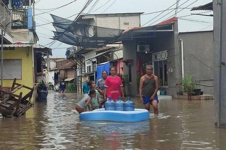 Warga Kelurahan Bandarharjo, Kecamatan Semarang Utara, Kota Semarang, melintasi banjir yang merendam kampungnya, Kamis (14/3/2024). Kata warga, banjir datang sejak Rabu (13/3/2024) petang.