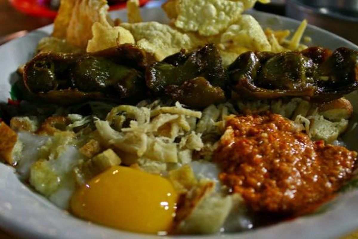 Bubur ayam spesial dengan tambahan kuning telur, emping, dan sate ampela.