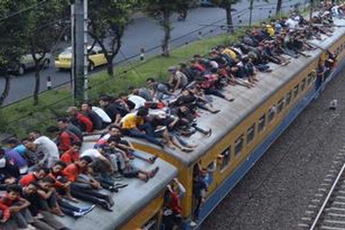 Saking penuhnya, penumpang Kereta Ekonomi Tanah Abang-Rangkas Bitung memenuhi atap gerbong kereta saat melintas di Kawasan Permata Hijau, Jakarta Selatan, Selasa (7/5/2013). Kondisi ini merupakan salah satu imbas penutupan KRL Ekonomi lintas Paraung Panjang-Tanah Abang yang mulai diberlakukan hari itu.

