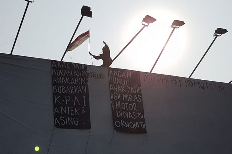 Seorang pria memanjat papan reklame pasar rebo, Rabu (12/9/2018)