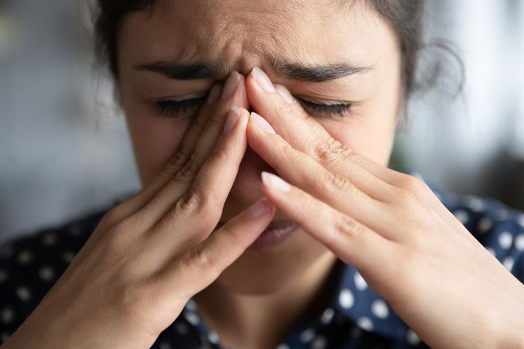 Seorang perempuan menyentuh wajah dengan tangan saat stres