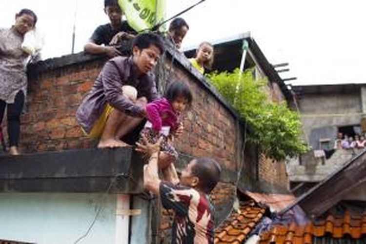 Warga turun dari atap rumahnya untuk dievakuasi Basarnas dari luapan Kali Ciliwung di Kelurahan Kebon Baru, Tebet, Jakarta Selatan, Sabtu (18/1/2014).