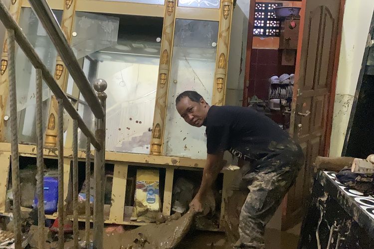 Andi Bram, saat dirinya tengah membersihkan material lumpur yang masuk kerumahnya akibat terbawa banjir, pada Senin (27/10/2025) di di Kampung Tugu Rt 3 Rw 3, Desa Cikahuripan, Kecamatan Cisolok, Kabupaten Sukabumi, Jawa Barat 