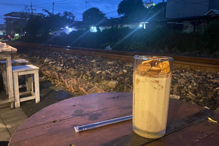 Menikmati minuman dengan pemandangan rel kereta api di sebelah kafe Selak Kopi, Malang, Jawa Timur. 