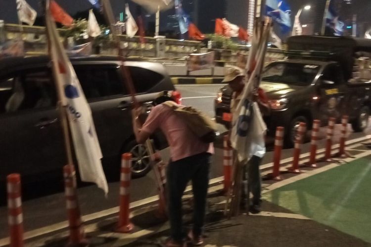 Potret petugas saat tertibkan alat peraga kampanye (APK) berupa bendera partai politik (parpol) di separator sepeda sepanjang Jalan HOS Cokroaminoto, flyover Rasuna Said, Minggu (14/1/2024).