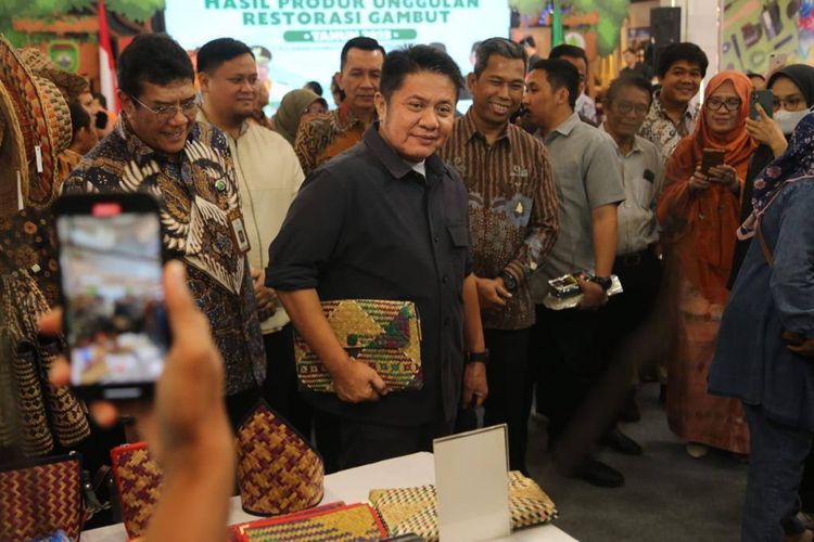 Gubernur Sumsel Herman Deru memegang tas hasil anyaman tanaman purun dari gambut, saat pameran produk hasil unggulan restorasi gambut di Palembang, Minggu (25/9/2023).